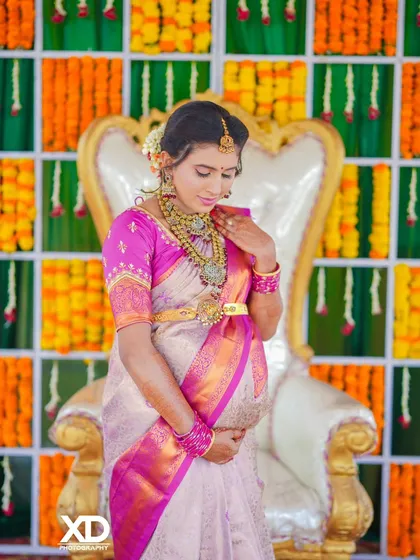 A serene portrait of the mother-to-be seated on the ceremonial chair, her hands cradling her belly in a moment of quiet connection.