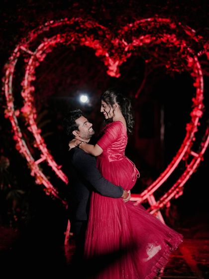 A romantic silhouette of a couple within a heart-shaped light installation, this time illuminated in red for a passionate feel.
