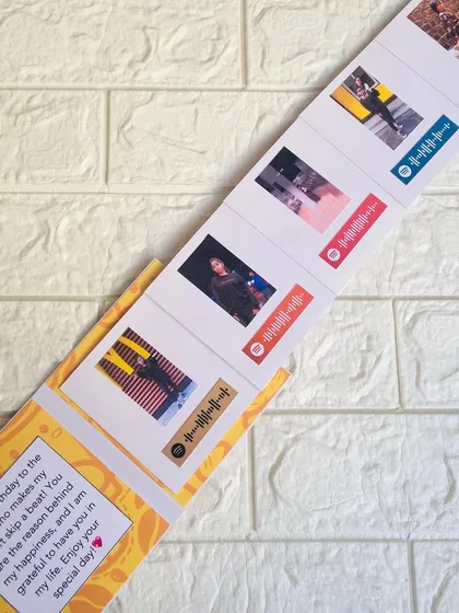 The slider card fully extended, revealing the series of five photos, each paired with a different song that tells your story.