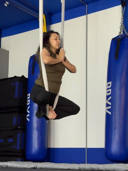 A floating prayer squat, using the hammock for support. This pose strengthens the legs and core while opening the hips.
