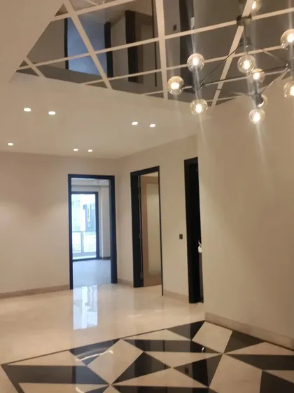 A view of the foyer in its final construction stages. The geometric marble floor inlay and modern chandelier are installed, showcasing key design features of the entrance area.