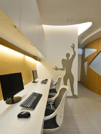 Workstations for senior architects are positioned within the open studio, with a sculptural wall element providing a sense of separation. The fluid design language continues across the ceiling and walls, unifying the entire office.