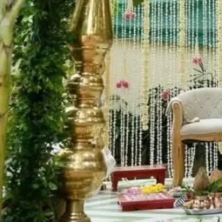 A detail shot of a traditional South Indian wedding mandap. The decor includes brass elements, lush greenery, and a curtain of tuberose, reflecting rich cultural heritage.