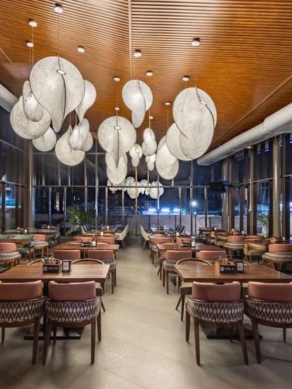 The interior dining space is adorned with large, sculptural pendant lights that resemble floating cocoons, adding an artistic touch to the high-ceilinged room.