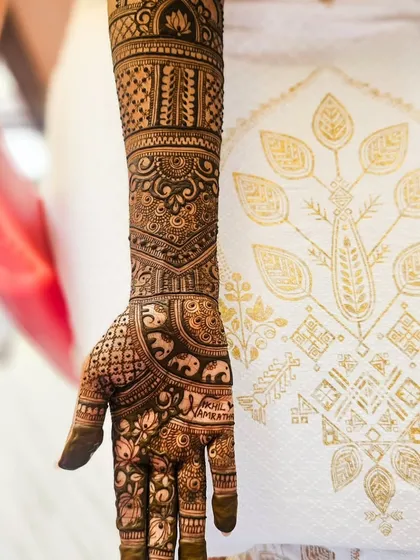 An artistic shot of the engagement arm henna, with a beautiful traditional Indian textile in the background.