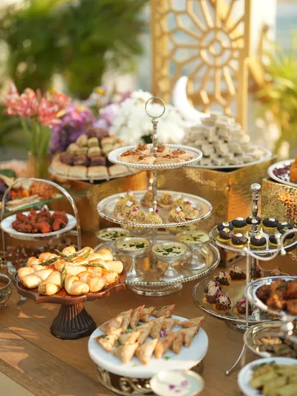 A lavish spread of appetizers and desserts for the House of Misu Iftaar party, featuring tiered platters and a mix of sweet and savoury treats.