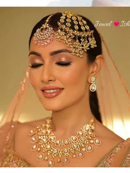 A close-up of the bride's serene expression, with her eyes closed, highlighting the beautiful details of her pastel pink and gold passa and tikka.