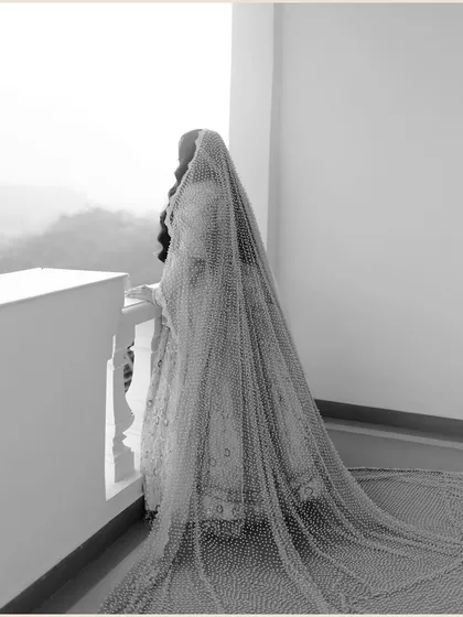 An artistic black and white shot of the bride from behind, her long, sheer veil cascading down and creating a beautiful, ethereal texture.
