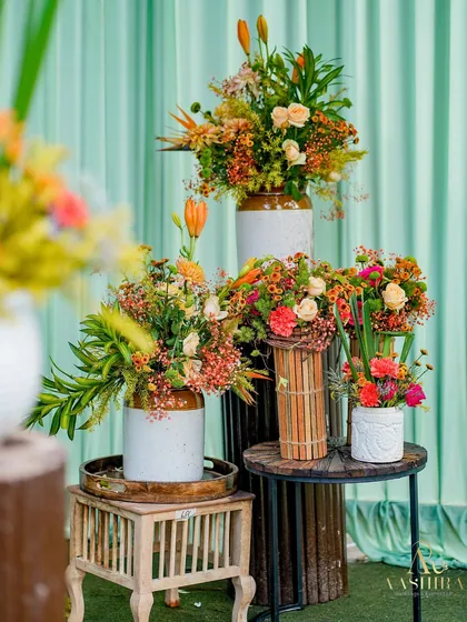 A beautiful display of floral arrangements on tiered pedestals, showcasing a variety of textures and warm, earthy colors.