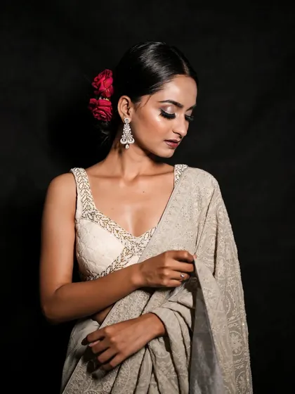 A graceful pose showing the intricate details of the embroidered saree. The soft lighting and the model's gentle expression create a timeless and beautiful portrait.