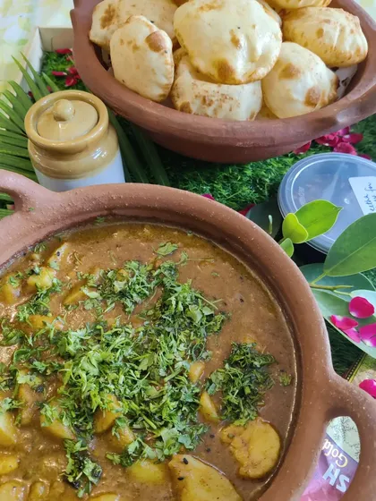 A traditional festive meal of Aloo ki Sabzi served with fluffy Kachoris. The potato curry is cooked in a clay pot to enhance its earthy flavours, making it a perfect dish for celebrations like Gangaur Teej.
