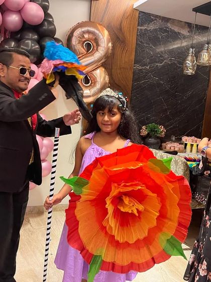This young volunteer is holding a giant flower that I just produced magically. I always make sure my helpers get to be a part of the most colourful and impressive tricks.