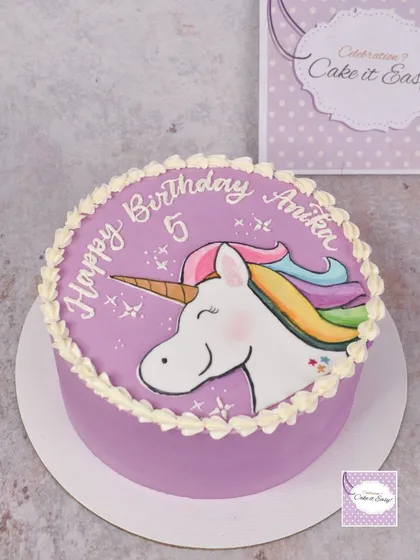 A hand-painted unicorn cake for a 5th birthday. The simple piped border lets the painted artwork shine.
