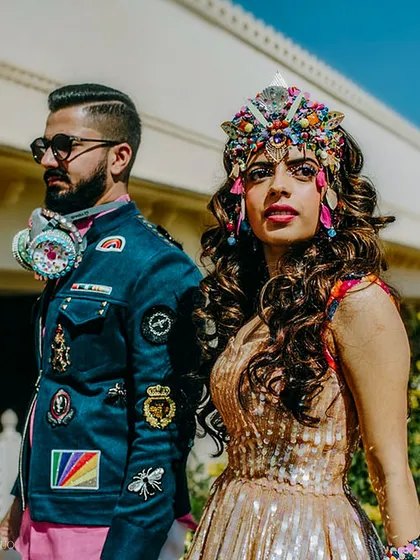 The couple fully embracing the festival theme. The bride wears a stunning, handmade headpiece, while the groom sports a custom-patched jacket and a decorated gas mask.