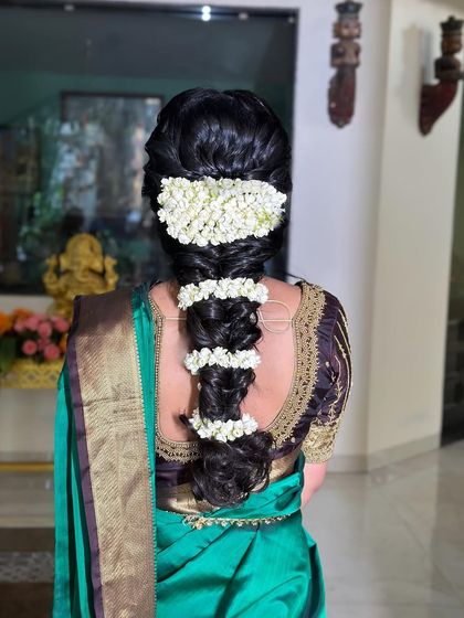This South Indian bridal hairstyle features a thick braid wrapped in fragrant jasmine flowers, or 'gajra', for a classic and timeless look.