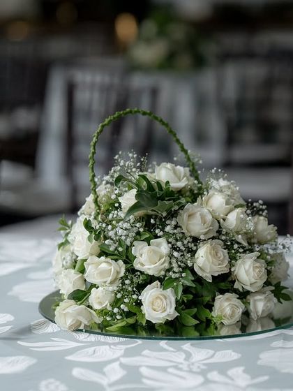 A basket-style centerpiece made of white roses, adding a touch of classic beauty to the guest tables.