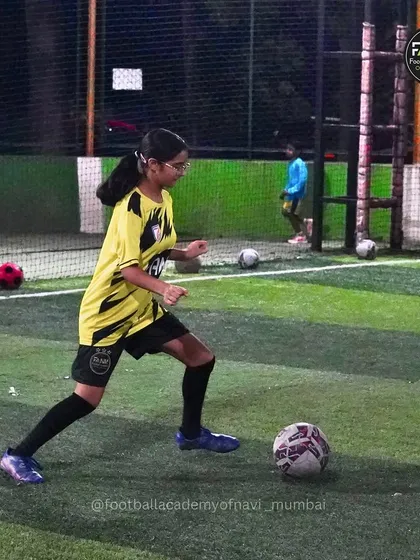A female player demonstrates confidence and control on the ball during an evening training session.