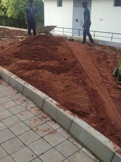 The process of sculpting the ground continues. A pile of earth is shaped and graded according to the design plan, creating the foundational contours of the future landscape.