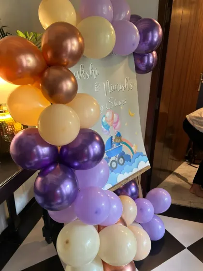 A close-up of a balloon garland in pastel purple, peach, and chrome for a baby shower welcome sign.