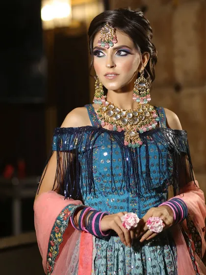 This blue lehenga with a cold-shoulder, fringed blouse is a super trendy option for a sangeet or mehendi. It's paired with beautiful floral jewelry.