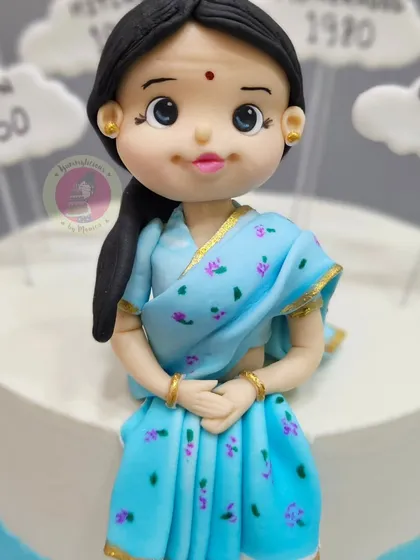 A close-up of the beautiful figurine made for a grandmother's milestone birthday, capturing her grace in a traditional blue saree.