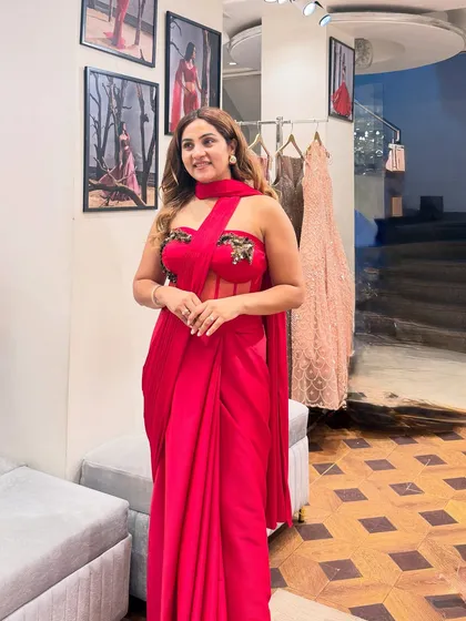 A side view of the red corset saree, showing how the drape falls beautifully. The sheer panel on the corset adds a modern touch, making it a sophisticated choice for a cocktail party or reception.