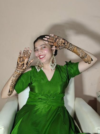 A happy client posing playfully with her intricate bridal mehendi.