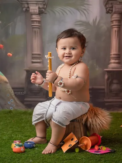Holding a firki, or kite string winder, this baby is ready for the festival. The rich background with peacock details adds an artistic touch to the photograph.