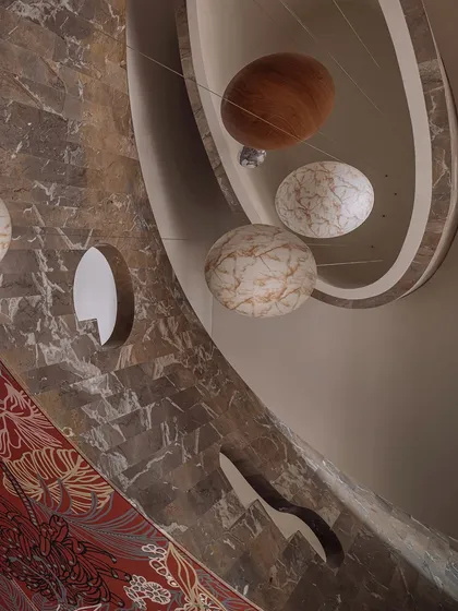 We transformed this stairwell into a surreal experience with a 'confetti carnival' installation. Oversized spheres of wood and marble are suspended by cables, and they light up in the evening to create a magical journey between floors.
