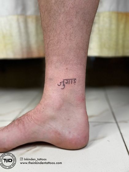 The Hindi word "Jugaad" tattooed on the ankle. This small tattoo captures a core concept of Indian resourcefulness and was created for a client from Wales who fell in love with the idea.