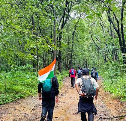 A trekker proudly carries the Indian flag while walking through the forest trail on the way to Dudhsagar Falls.