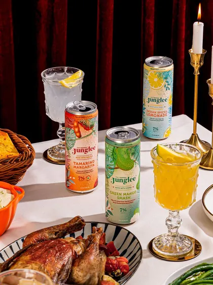A festive dinner table setting featuring the full range of Junglee's canned cocktails, showing how the product can be part of a larger celebratory meal.