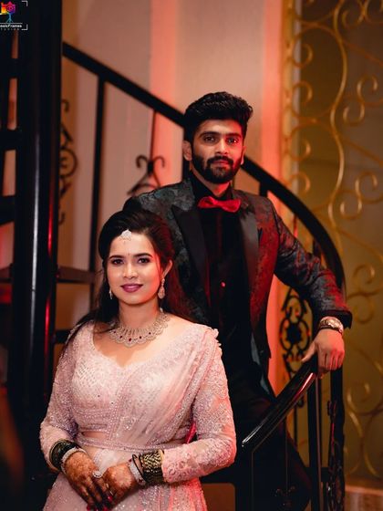 A classic power pose on the stairs. This reception photo captures the couple in a stylish and confident embrace, highlighted by warm, dramatic lighting.