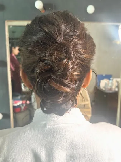 A behind the scenes look at creating a messy bun, showing the client in her robe before the final reveal.