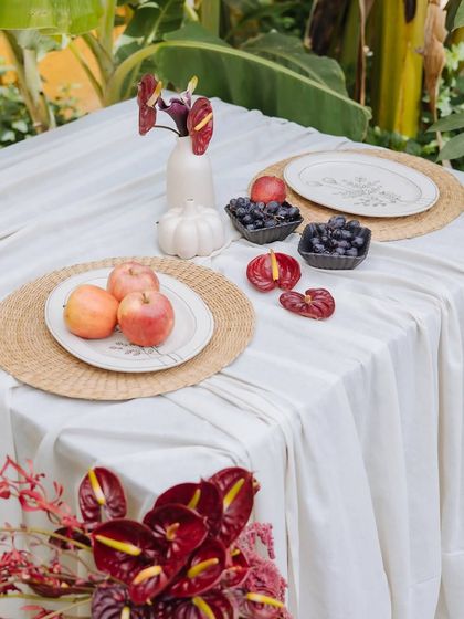 A closer look at the Orchard Table setting. Fresh apples and grapes are placed on the table, complementing the deep red of the anthurium flowers.