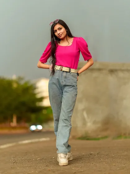 A confident walk towards the camera, this shot captures a casual street style look with a bright pink top and baggy jeans.