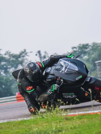 A rider on a black superbike kicks up dirt as they use every inch of the track. This is what fearless, passionate riding looks like.