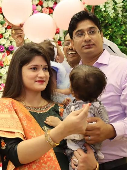 A candid shot of a family interacting during a celebration, with a beautiful flower wall in the background.