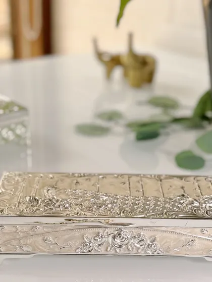 A keepsake that holds more than jewels. Featuring intricate silver engraving of a peacock and delicate pearl enamel, this rectangular jewellery box is a timeless treasure in itself.