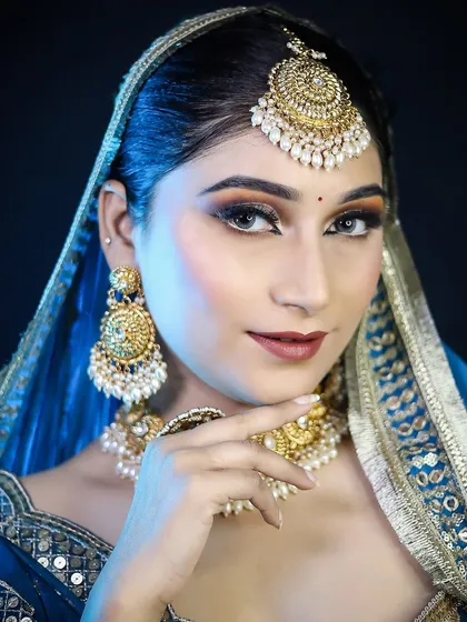 A regal bridal look in a deep blue lehenga. The cool-toned makeup with a sharp, defined eye complements the cool tones of the outfit and the silver-gold jewelry.