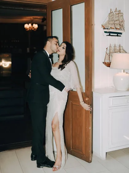 A stolen kiss against a doorway during their cocktail party. This candid portrait captures a moment of spontaneous romance amidst the celebration, showing that intimacy can be found anywhere.