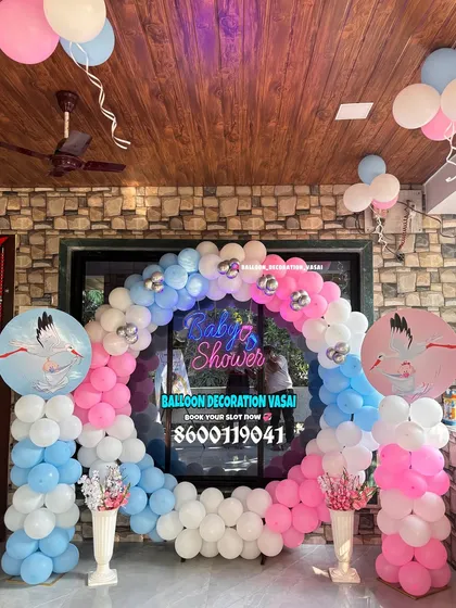 This circular balloon arch in pink, blue, and white creates a perfect frame for photos. The "Baby Shower" neon sign in the center adds a modern, bright focal point to this balcony decoration.