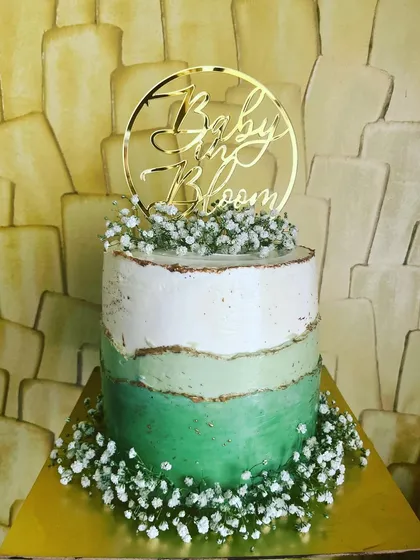 Welcome a new arrival with a beautiful baby shower cake. This 'Baby in Bloom' cake features a chocolate and mango flavor combination with a delicate green ombre buttercream design, adorned with fresh baby's breath for a touch of natural elegance.