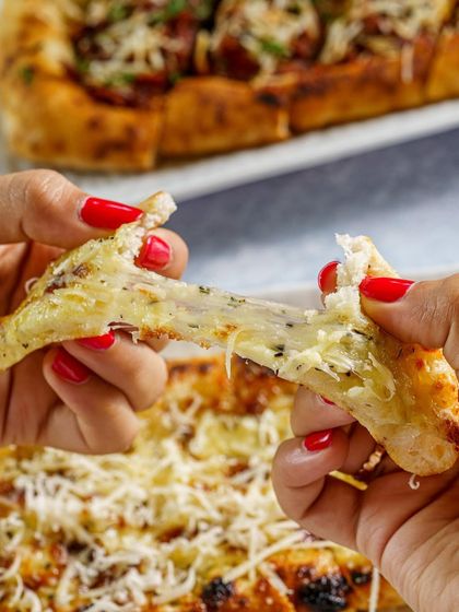 The cheese pull is the ultimate money shot for anything with cheese. This photo of a cheesy garlic bread being pulled apart is designed to create an instant craving and highlight the indulgent nature of the dish.