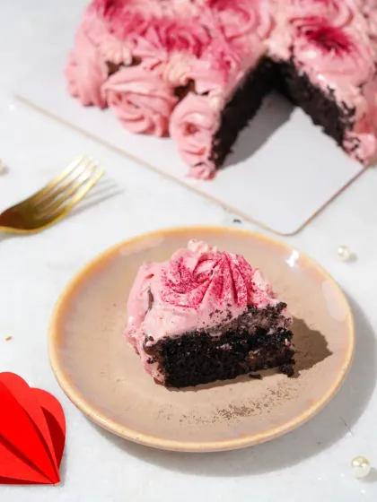 A single slice of a heart-shaped rose cake, beautifully plated and ready to be enjoyed. The lighting is soft and romantic.