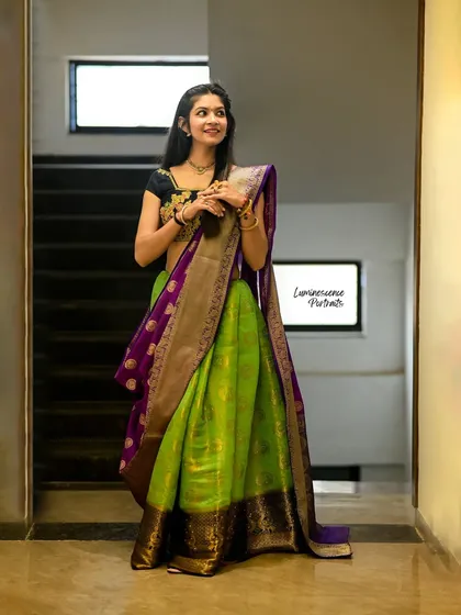A classic pose showcasing the beautiful drape of a traditional half-saree in a bright, indoor setting.