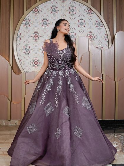 A joyful and radiant full-length shot of the purple gown. This image captures the dress in its entirety, showing off the beautiful A-line silhouette and intricate patterns on the skirt.