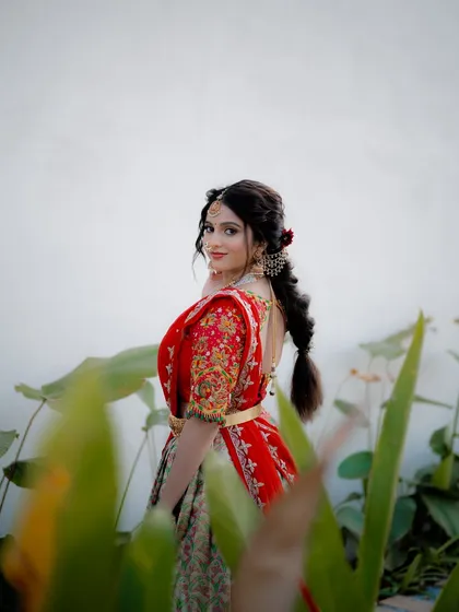 A candid shot of actress Niveditha Gowda in a traditional half saree, framed by foliage. This creative composition adds a sense of intimacy and natural beauty to the portrait.