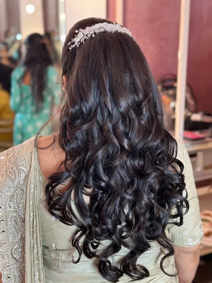 A voluminous ponytail with soft curls, finished with a sparkling hair accessory for a chic party look.