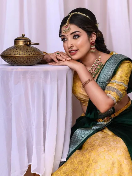 A beautiful engagement look with a yellow and green half-saree, showing a soft and radiant makeup style.